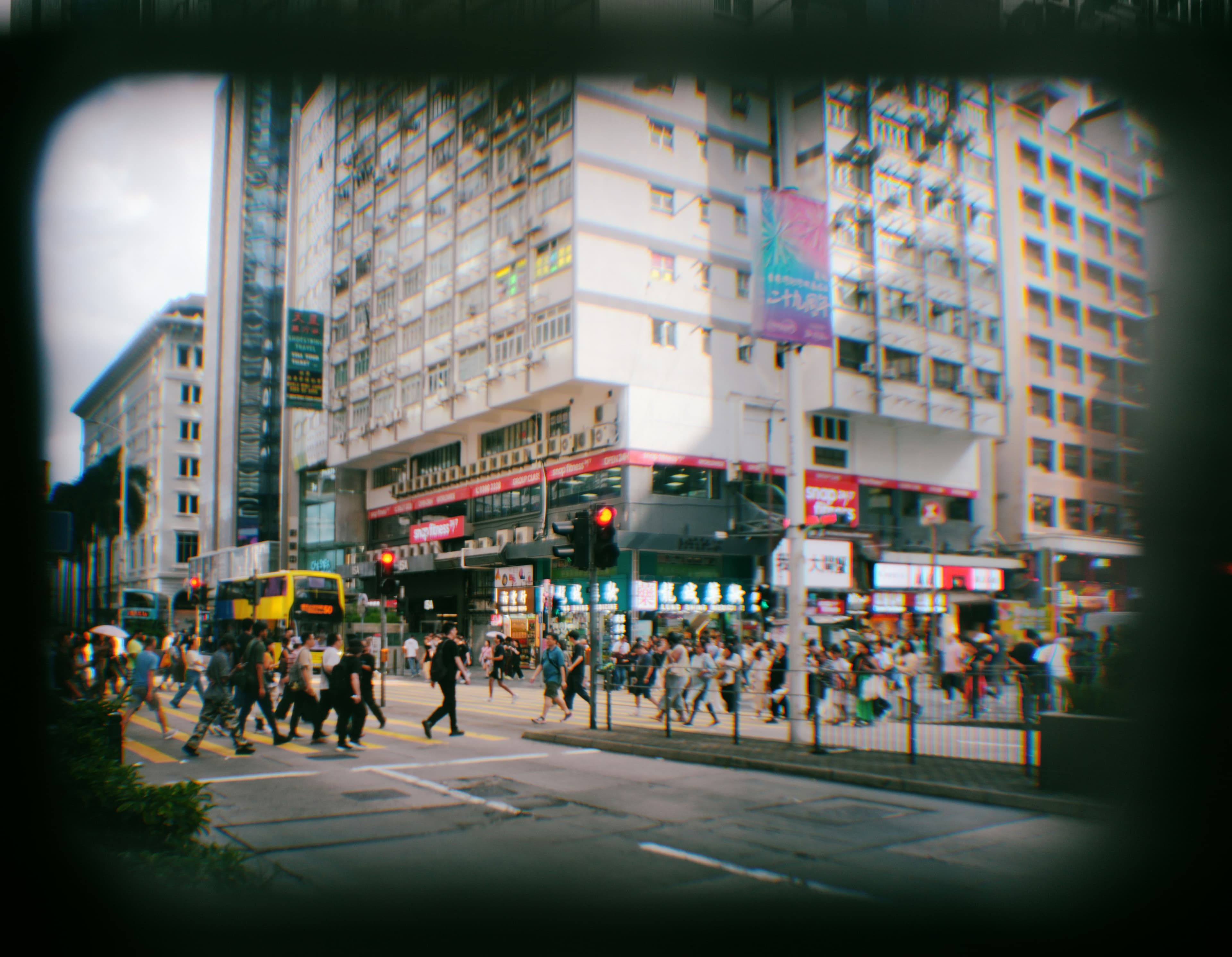 Crowds crossing a busy city street beneath tall buildings