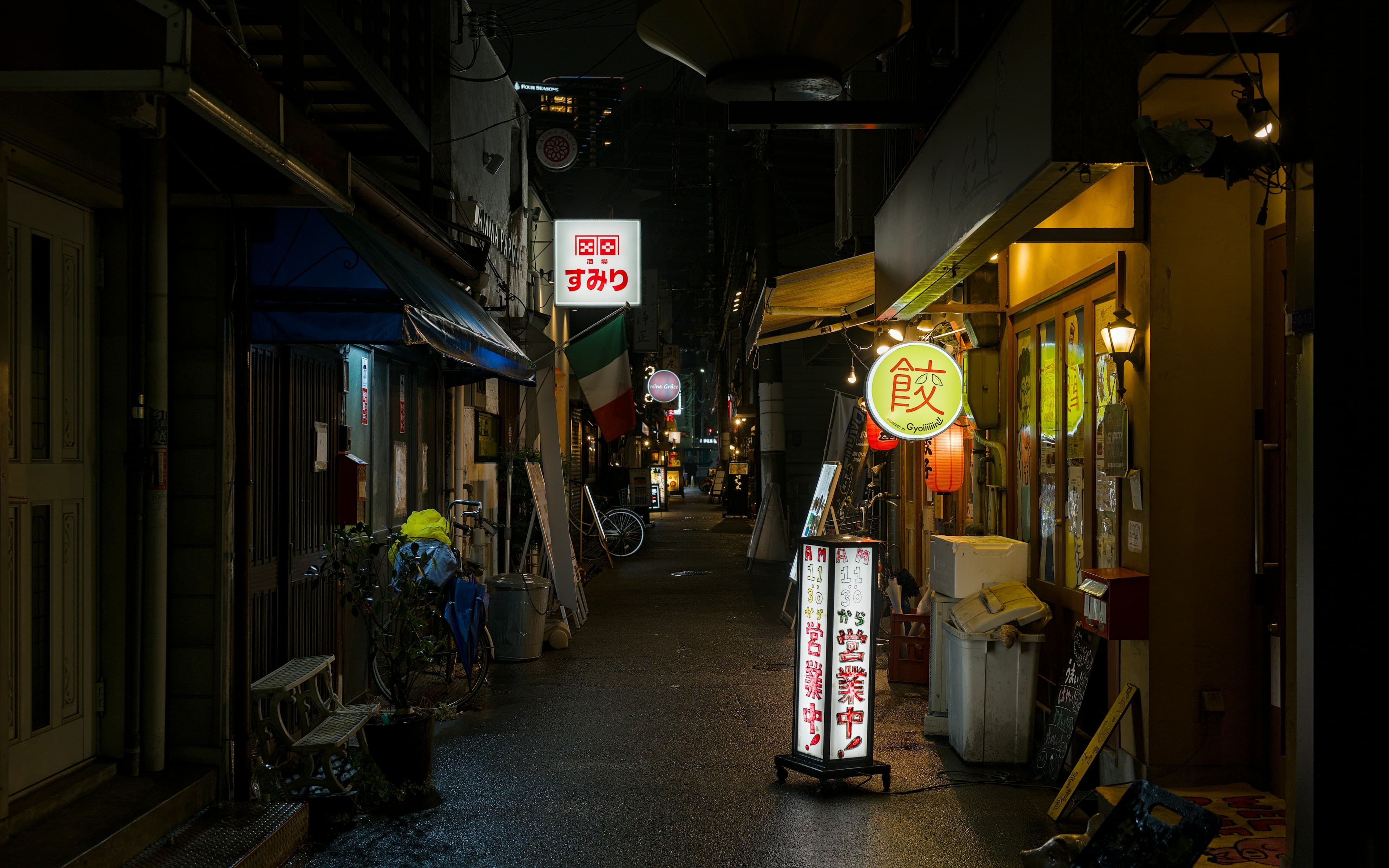 A narrow street of independent restaurants glowing after dark