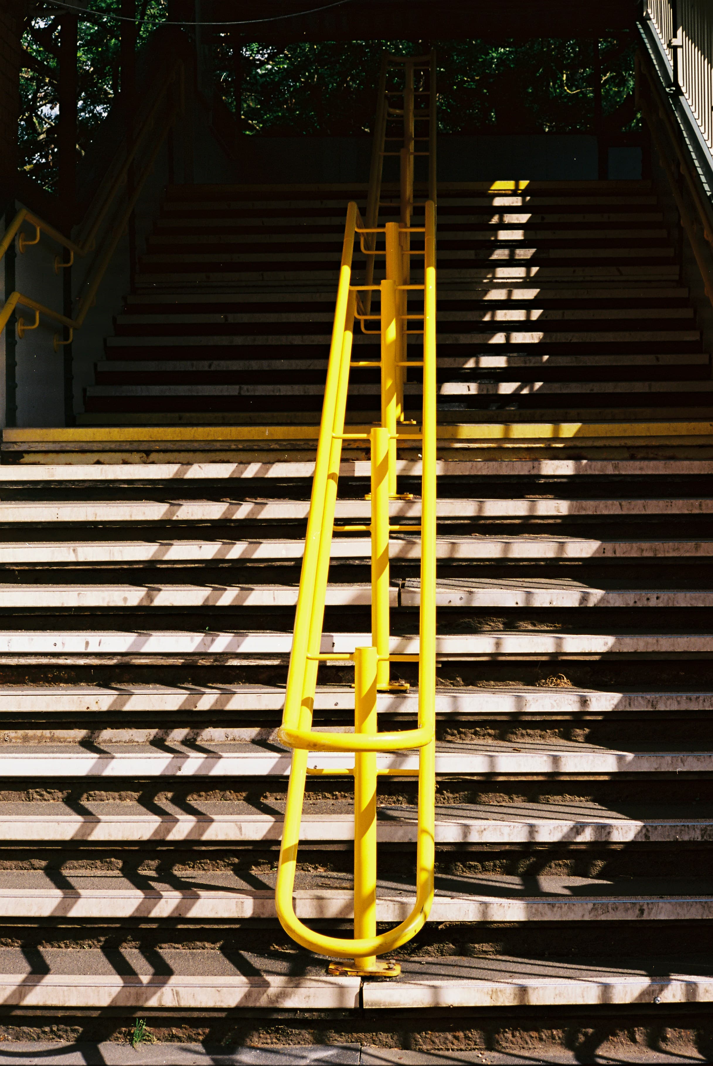 A sunlit staircase with a vivid yellow handrail